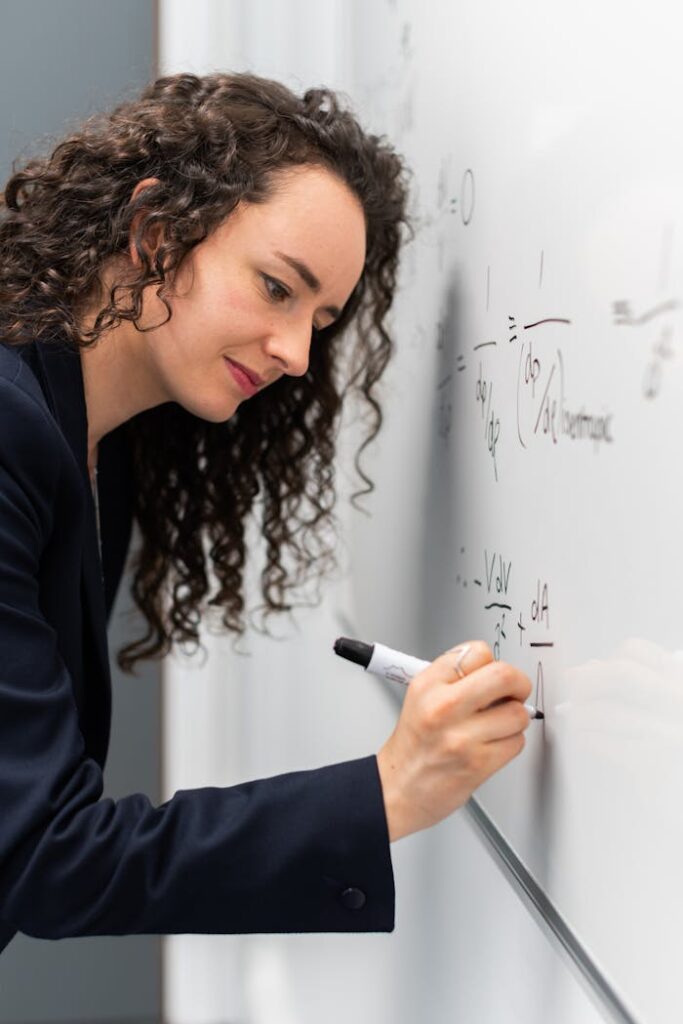 pexels-photo-3862126 Female engineer solving equations on whiteboard with focus and precision.
