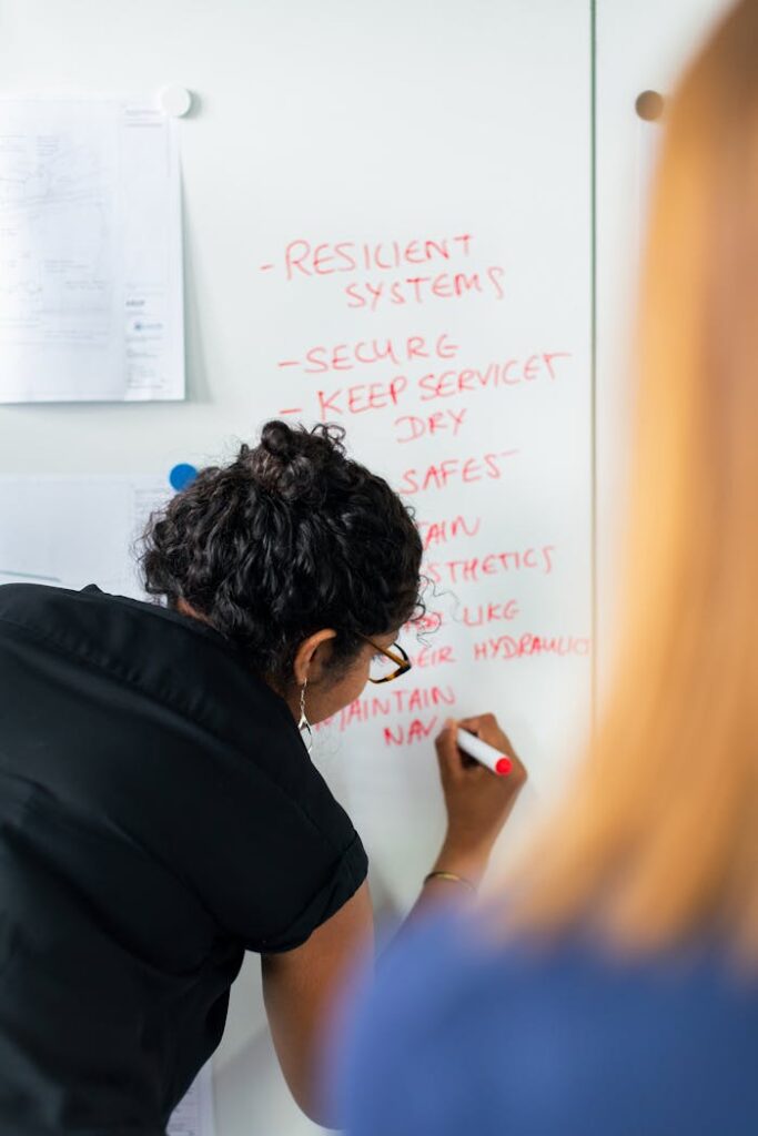 pexels-photo-3862380 Female engineer writing strategy on a whiteboard during a business meeting.